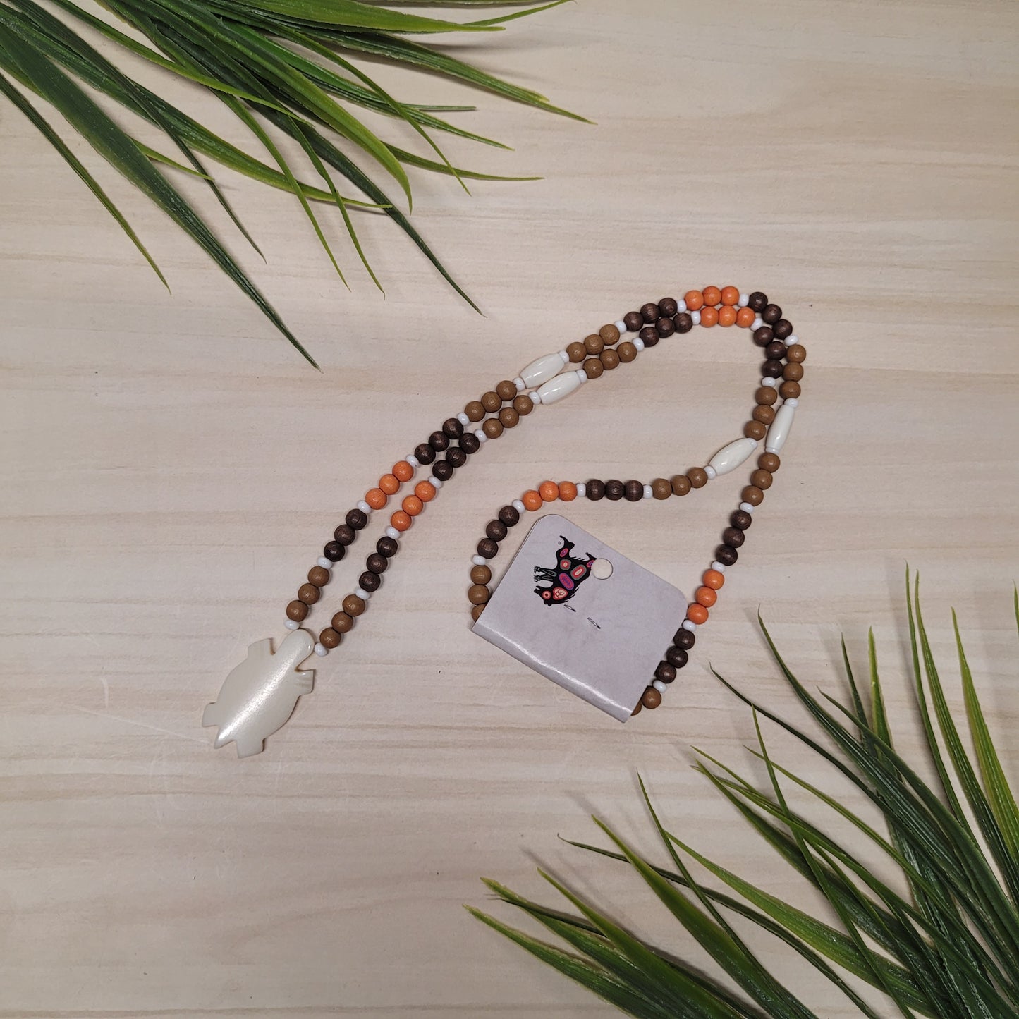 Collier de billes de bois oranges, brunes et marron avec pendentif en os