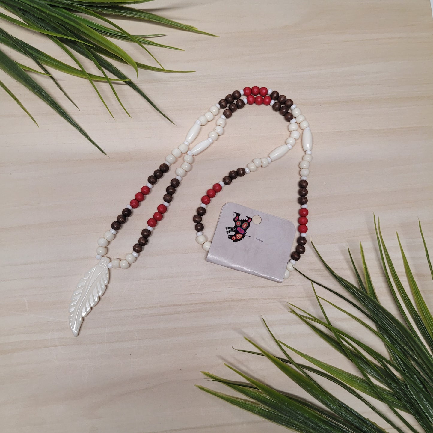 Collier de billes de bois rouges, brunes et blanches avec pendentif en os